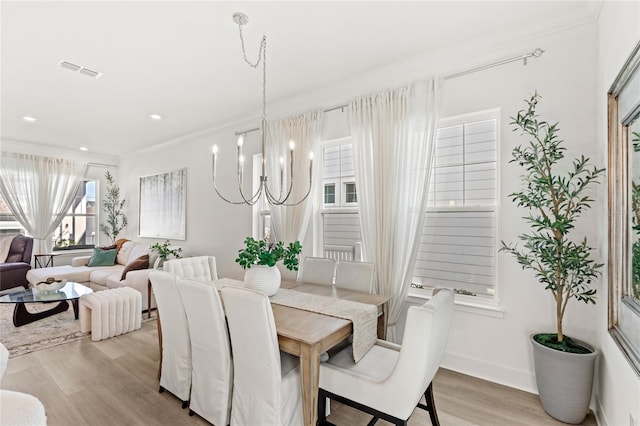 dining space with a notable chandelier, crown molding, visible vents, light wood-style floors, and baseboards