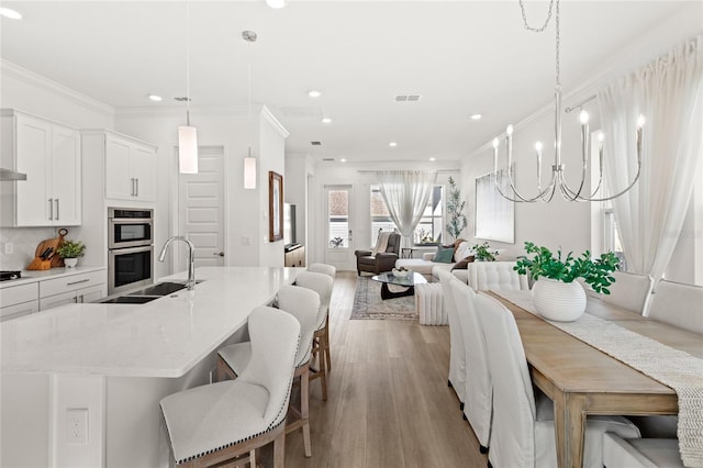 dining space featuring light wood-type flooring, an inviting chandelier, ornamental molding, and recessed lighting