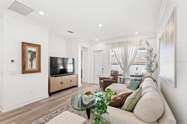 living area with baseboards, light wood-style flooring, visible vents, and crown molding