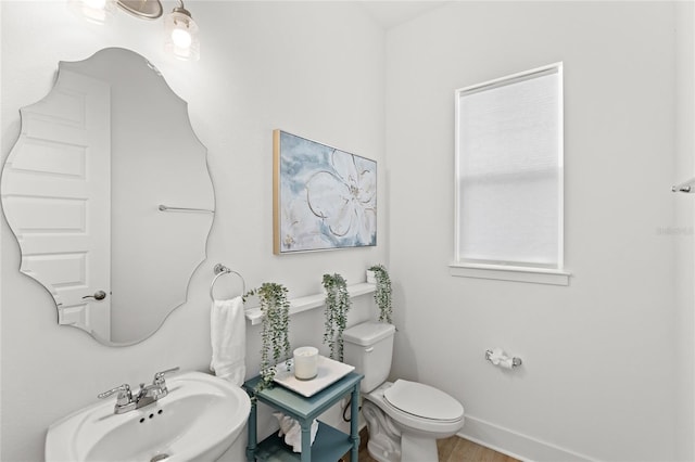 bathroom featuring wood finished floors, a sink, toilet, and baseboards