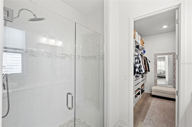 full bath featuring a shower stall, a spacious closet, and wood finished floors