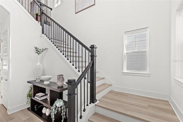 stairs with a towering ceiling, baseboards, and wood finished floors