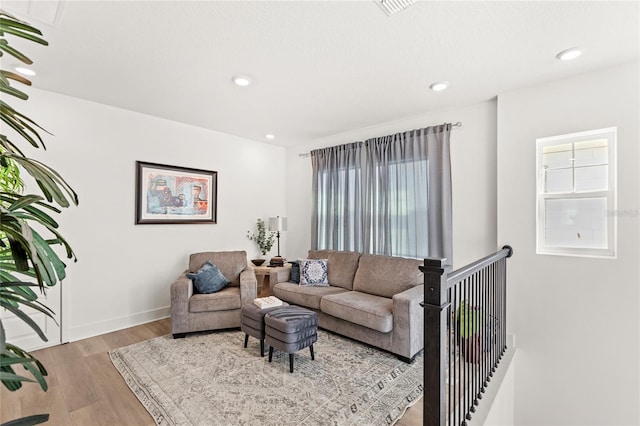 living area with baseboards, visible vents, light wood-style flooring, and recessed lighting