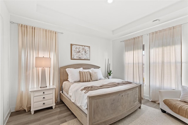 bedroom featuring light wood-style floors and a raised ceiling