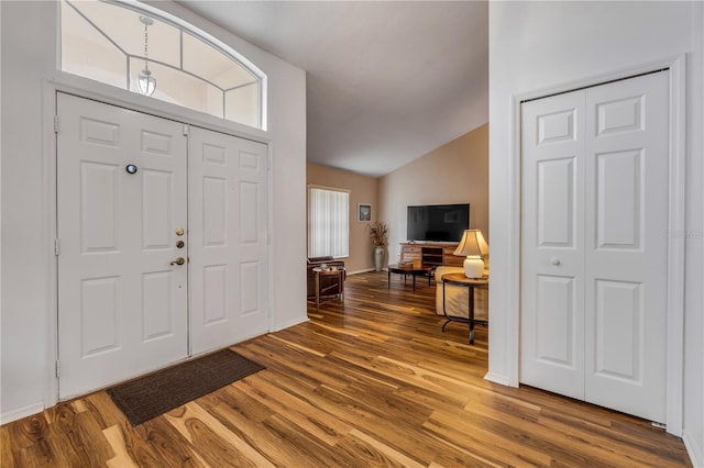 foyer entrance with vaulted ceiling, baseboards, and wood finished floors