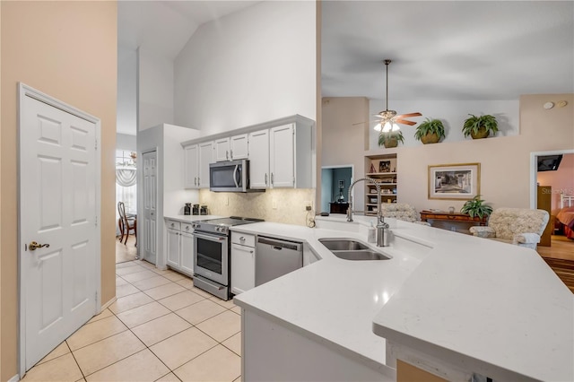 kitchen featuring light tile patterned floors, white cabinets, a peninsula, stainless steel appliances, and a sink
