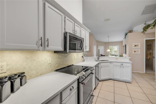 kitchen with light tile patterned flooring, stainless steel appliances, a peninsula, a sink, and light countertops