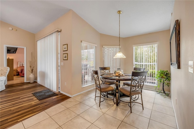 dining space with lofted ceiling, light tile patterned floors, and baseboards