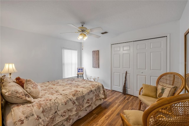 bedroom with a textured ceiling, ceiling fan, a closet, and wood finished floors