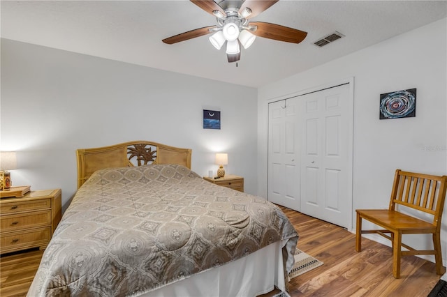 bedroom with a closet, visible vents, ceiling fan, and wood finished floors