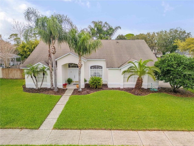 view of front of house featuring a shingled roof, a front yard, and stucco siding