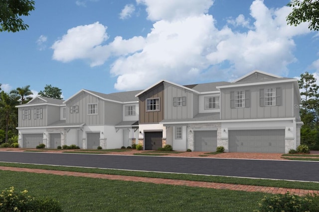 view of front of house with an attached garage, stone siding, decorative driveway, board and batten siding, and a front yard