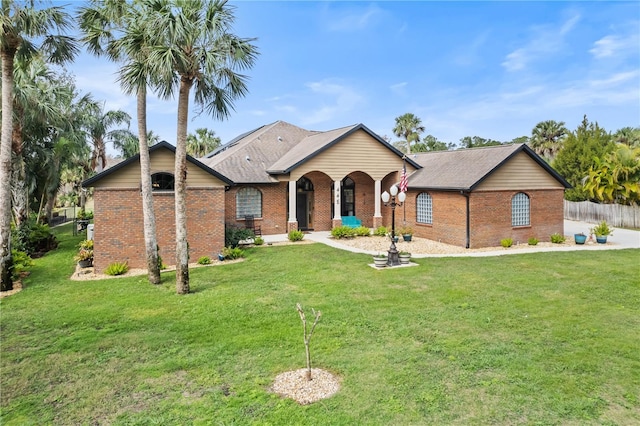 ranch-style home with a shingled roof, brick siding, fence, and a front lawn