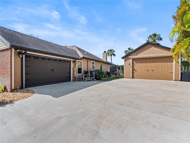 single story home with a garage, an outbuilding, brick siding, and a shingled roof