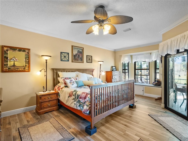 bedroom with visible vents, light wood-style flooring, ornamental molding, a textured ceiling, and baseboards