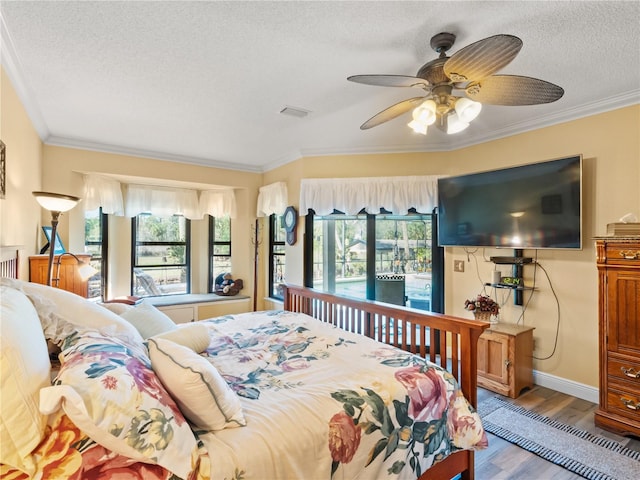 bedroom with crown molding, visible vents, ceiling fan, a textured ceiling, and wood finished floors