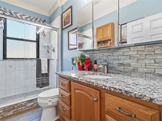 full bath with a stall shower, toilet, crown molding, vanity, and backsplash