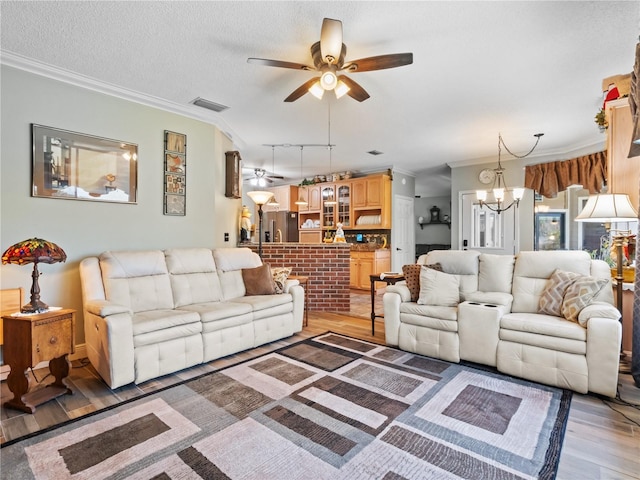 living room with light wood-style floors, a textured ceiling, visible vents, and crown molding