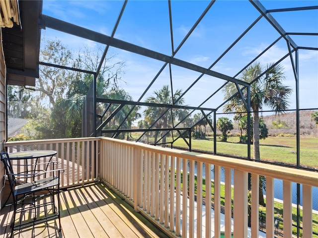 wooden terrace with a lanai, a water view, and a yard