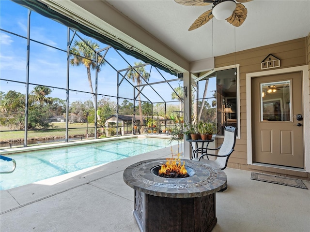 pool featuring a ceiling fan, glass enclosure, a patio, and a fire pit