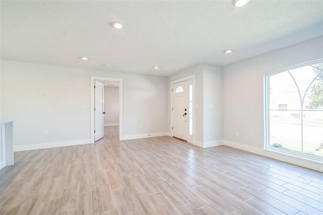 unfurnished living room featuring light wood finished floors, baseboards, and a wealth of natural light