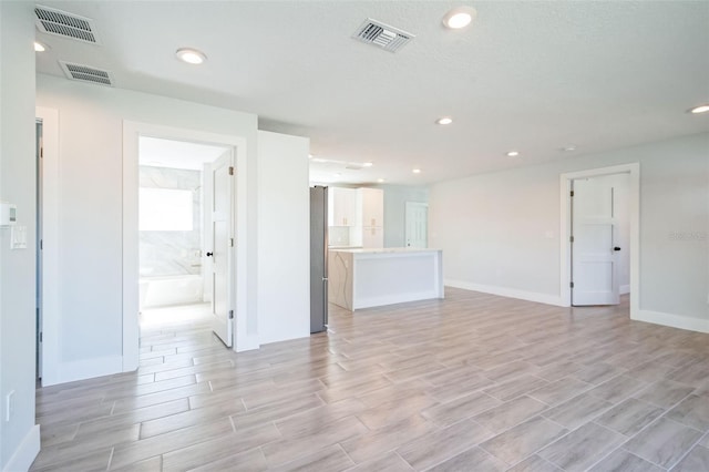 unfurnished living room featuring visible vents, recessed lighting, and baseboards