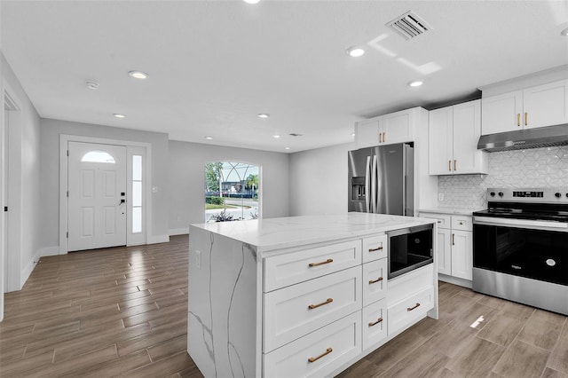 kitchen with visible vents, light wood-style flooring, stainless steel appliances, under cabinet range hood, and tasteful backsplash