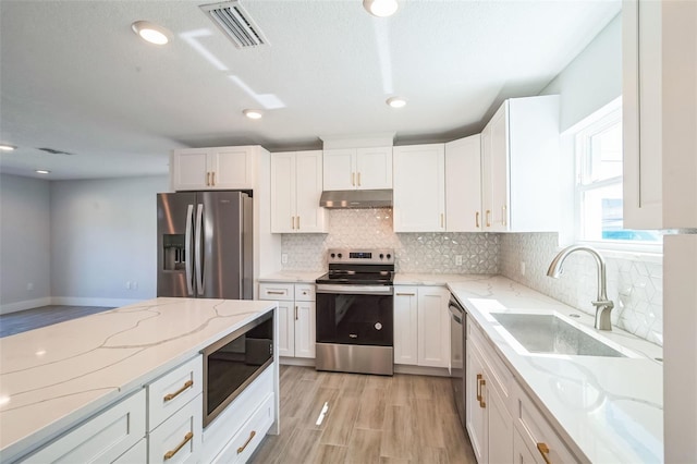 kitchen with visible vents, under cabinet range hood, a sink, white cabinetry, and appliances with stainless steel finishes