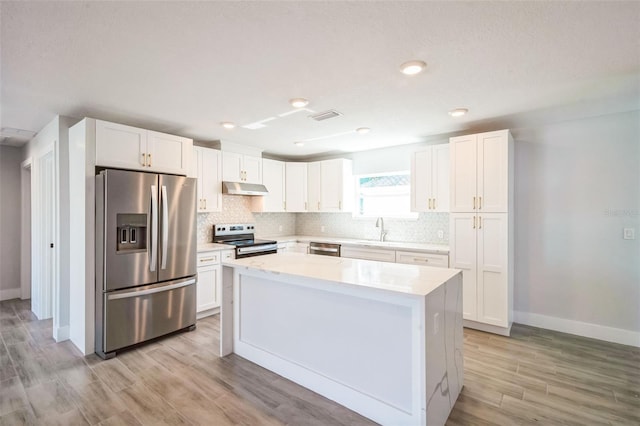 kitchen featuring visible vents, under cabinet range hood, decorative backsplash, appliances with stainless steel finishes, and a sink