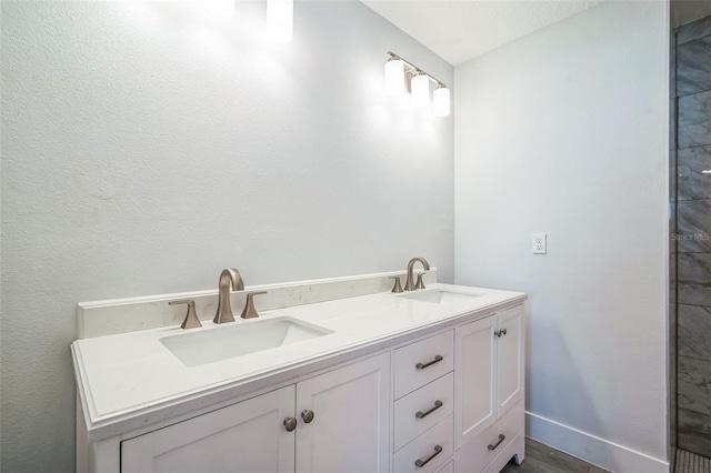 full bathroom with double vanity, wood finished floors, baseboards, and a sink