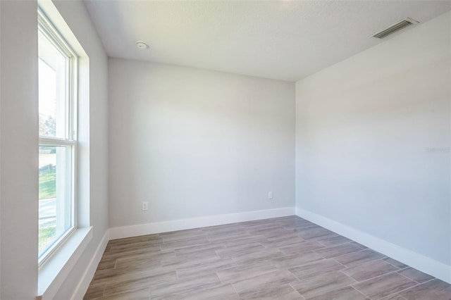 spare room with visible vents, light wood-style flooring, and baseboards