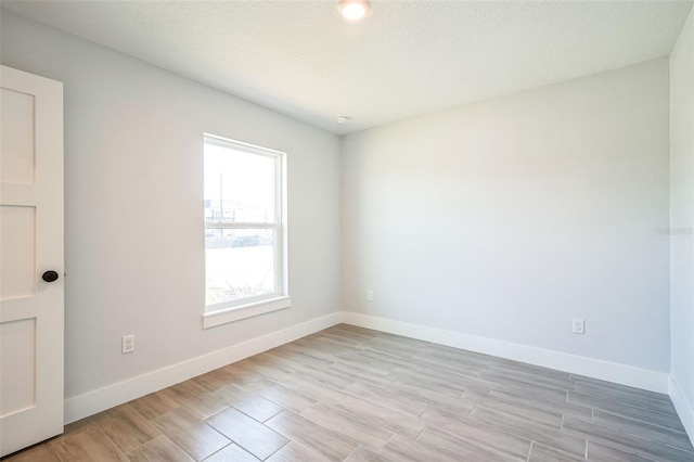 spare room featuring baseboards and light wood-style floors