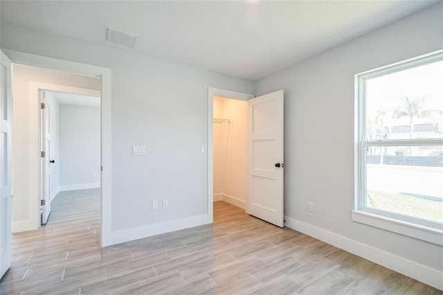 unfurnished bedroom featuring light wood finished floors, visible vents, and baseboards