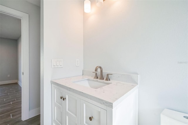 bathroom featuring toilet, vanity, baseboards, and wood finished floors