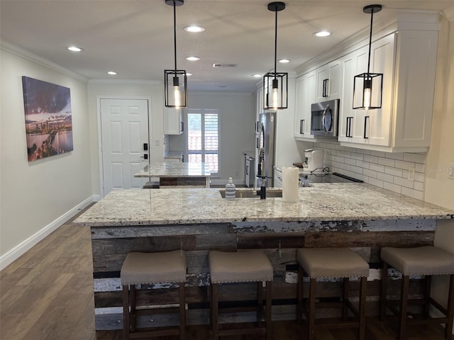 kitchen with a peninsula, appliances with stainless steel finishes, and crown molding