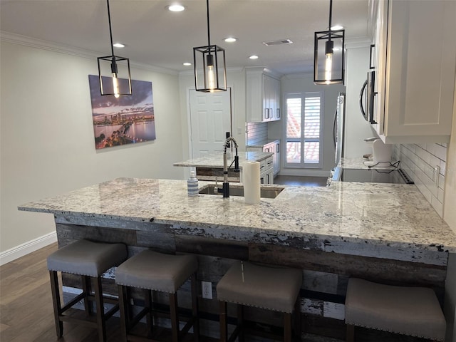 kitchen featuring white cabinetry, backsplash, crown molding, and stainless steel microwave