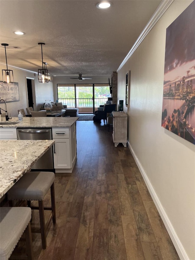 kitchen with ornamental molding, open floor plan, dark wood-style flooring, decorative light fixtures, and white cabinetry