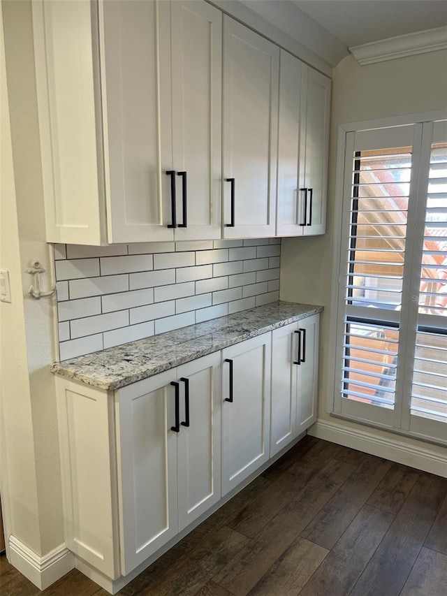 bar with tasteful backsplash, crown molding, dark wood finished floors, and baseboards