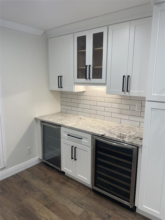 bar featuring a bar, beverage cooler, decorative backsplash, and dark wood-style flooring