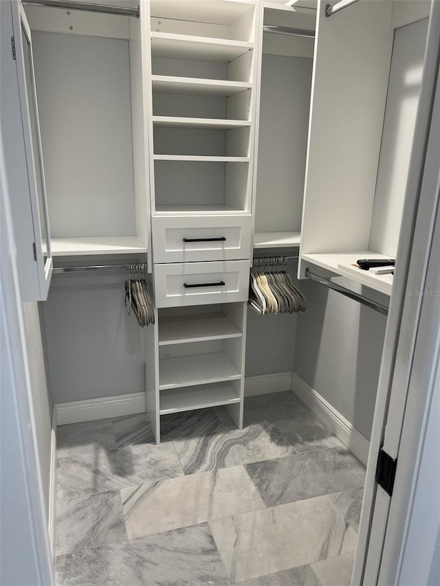 walk in closet featuring marble finish floor