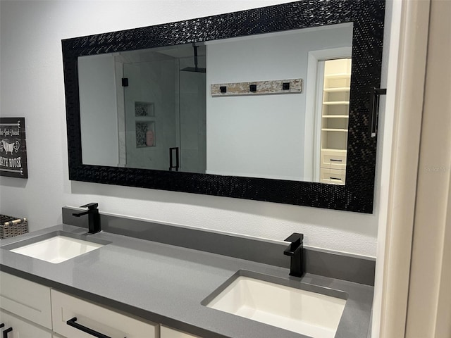 bathroom with a sink, a shower stall, and double vanity