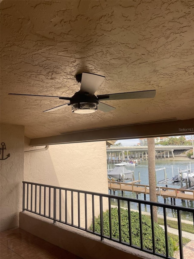 balcony featuring a water view and a ceiling fan