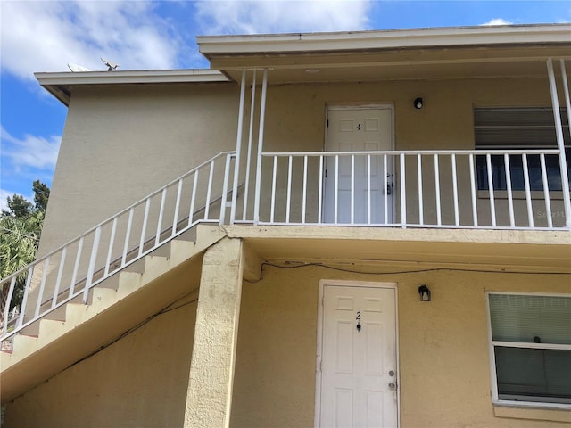 property entrance featuring a balcony and stucco siding