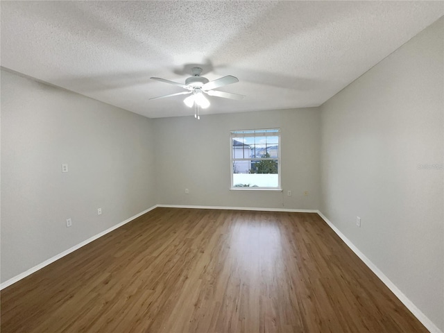 spare room featuring a textured ceiling, dark wood finished floors, a ceiling fan, and baseboards