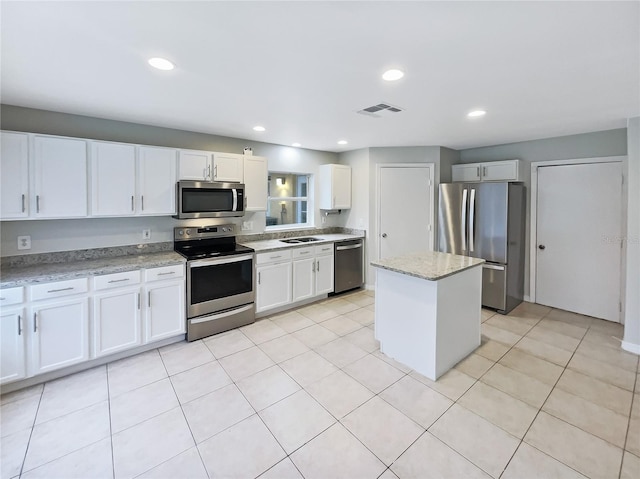 kitchen featuring light stone counters, a center island, visible vents, appliances with stainless steel finishes, and white cabinetry