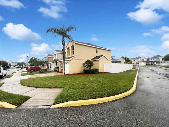 view of home's exterior featuring stucco siding, a residential view, fence, and a yard