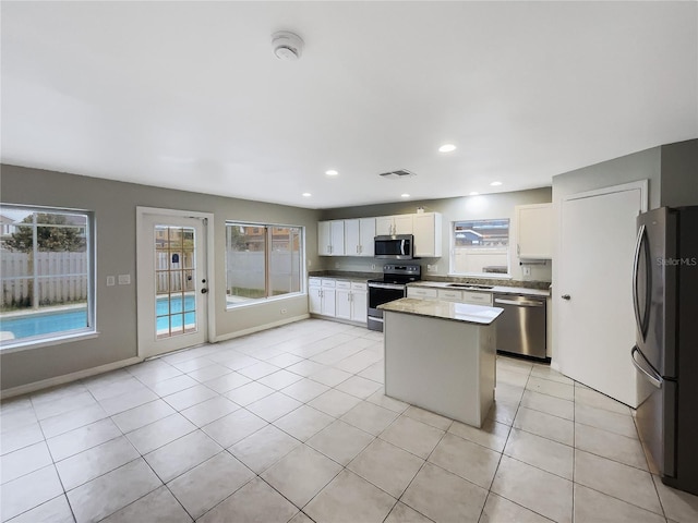 kitchen with stainless steel appliances, a kitchen island, visible vents, and white cabinets