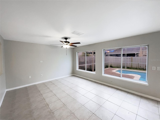 empty room featuring visible vents, ceiling fan, baseboards, and light tile patterned floors