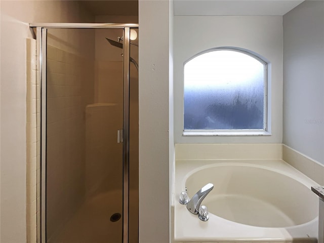 full bathroom with a shower stall and a bath