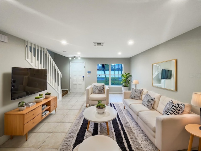 living area with light tile patterned floors, stairs, and visible vents